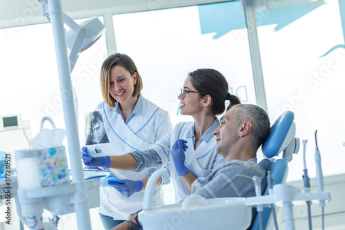 In a busy dental office, a group of dentists examining x-ray image of the patient's teeth to provide accurate diagnoses and develop effective treatment plans.