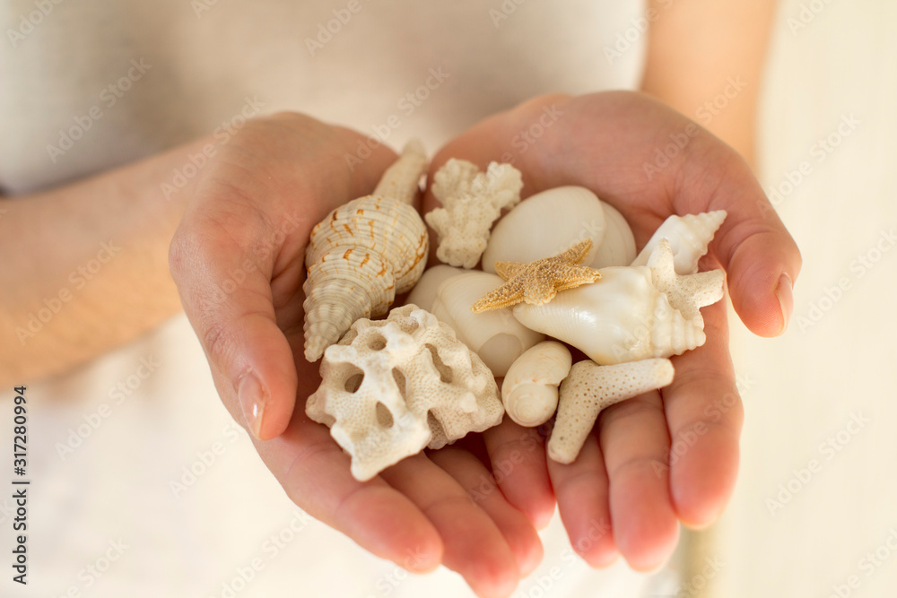 young woman holding white sea shells and corals