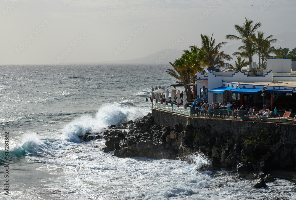 Waves crash onto a cafe by the sea