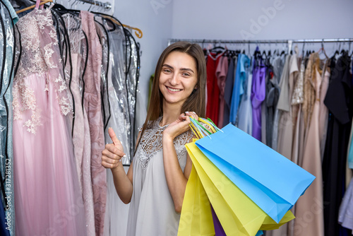 Happy young woman with shopping bags in dress store