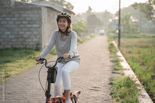 Asian women wear helmets to ride folding bikes for sports in the morning
