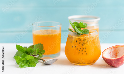 Passion fruit juice in a glass on a white wooden floor in a light blue background, summer drinks nonalcoholic