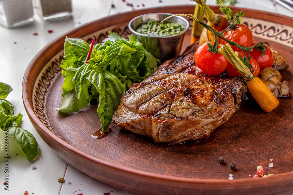 Pork entrecote served with grilled vegetables, mushrooms and pesto sauce, restaurant dish, Horizontal orientation Pork entrecote served with grilled vegetables, mushrooms and pesto sauce, restaurant dish, Horizontal orientation