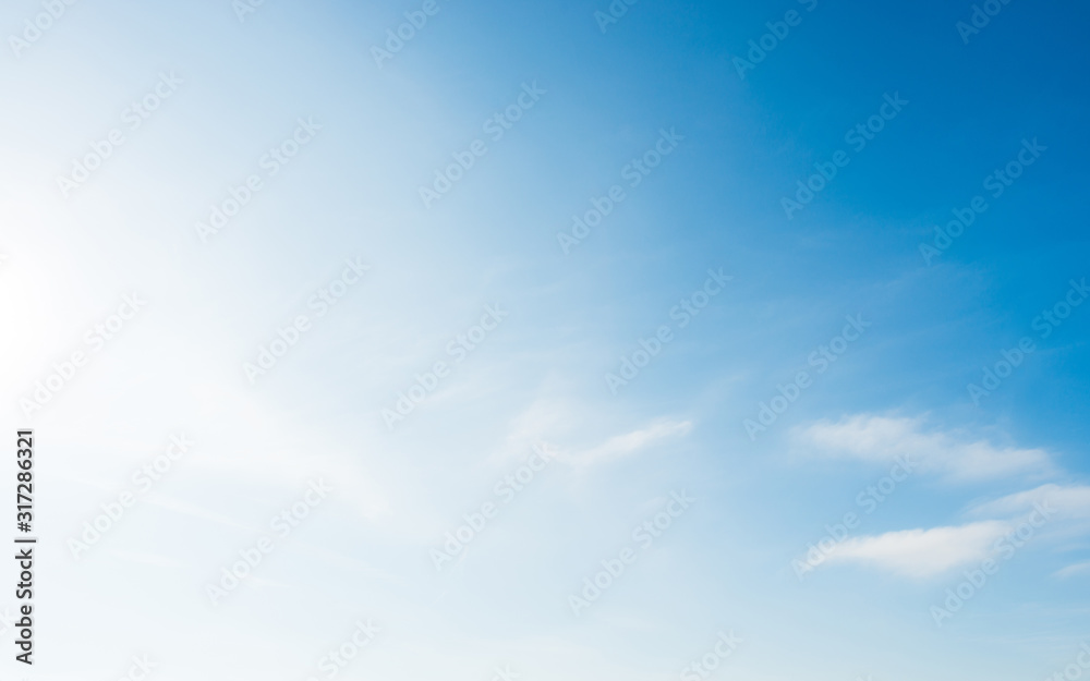 Soft blue sky with small white clouds and bright sun light