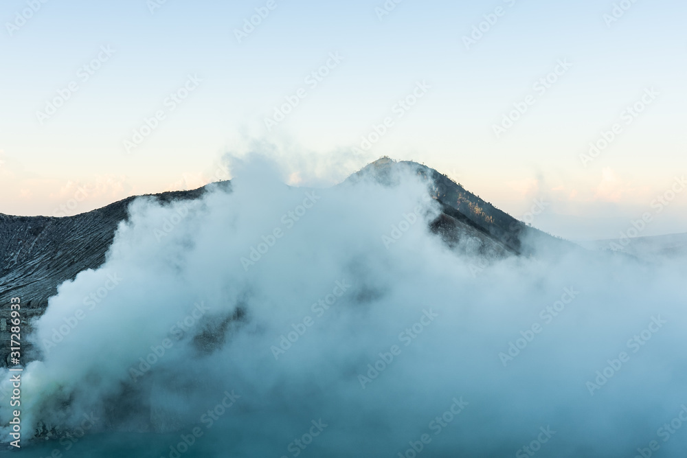 Beautiful Landscape mountain and blue lake with smoke sulfur in the morning in a Kawah Ijen volcano.