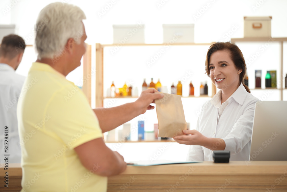 Pharmacist giving medicine to customer in drugstore Pharmacist giving medicine to customer in drugstore