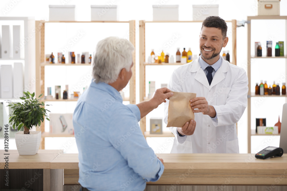 Fototapeta premium Pharmacist giving medicine to customer in drugstore
