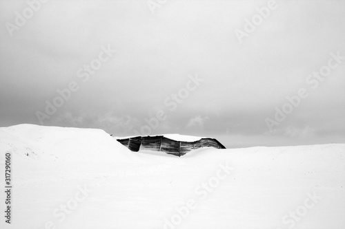 Old wooden barn covered with snow in black and white