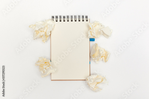 Many crumpled balls near notebook with a copy space on a white paper background. Idea concept. View from above.