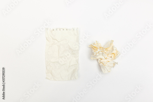 Crumpled piece of paper from notebook near crumpled paper balls on white paper background. Idea concept. Top view.