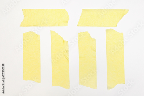 Set of yellow paper tapes on a white background. Torn horizontal and vertical yellow sticky tape of different size, adhesive pieces. View from above.