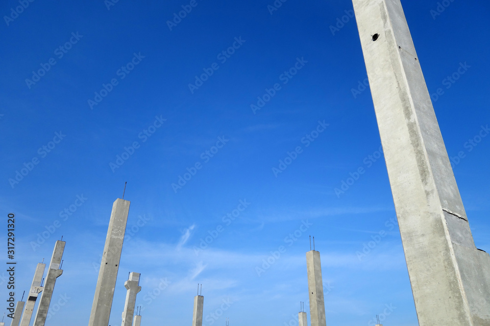 Concrete construction posts against blue sky.