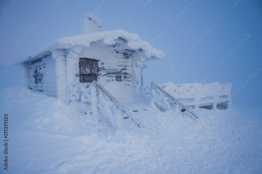 A snow-covered cabin on a mountain in Finnish Lapland, like the house of a snowman or Santa Claus from ice and snow in a winter fairy tale
