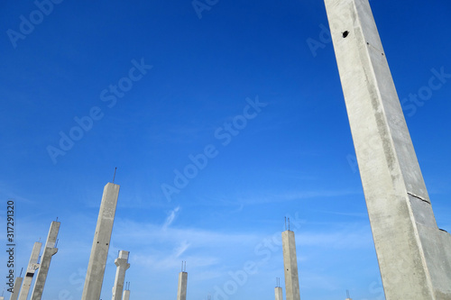 Concrete construction posts against blue sky.