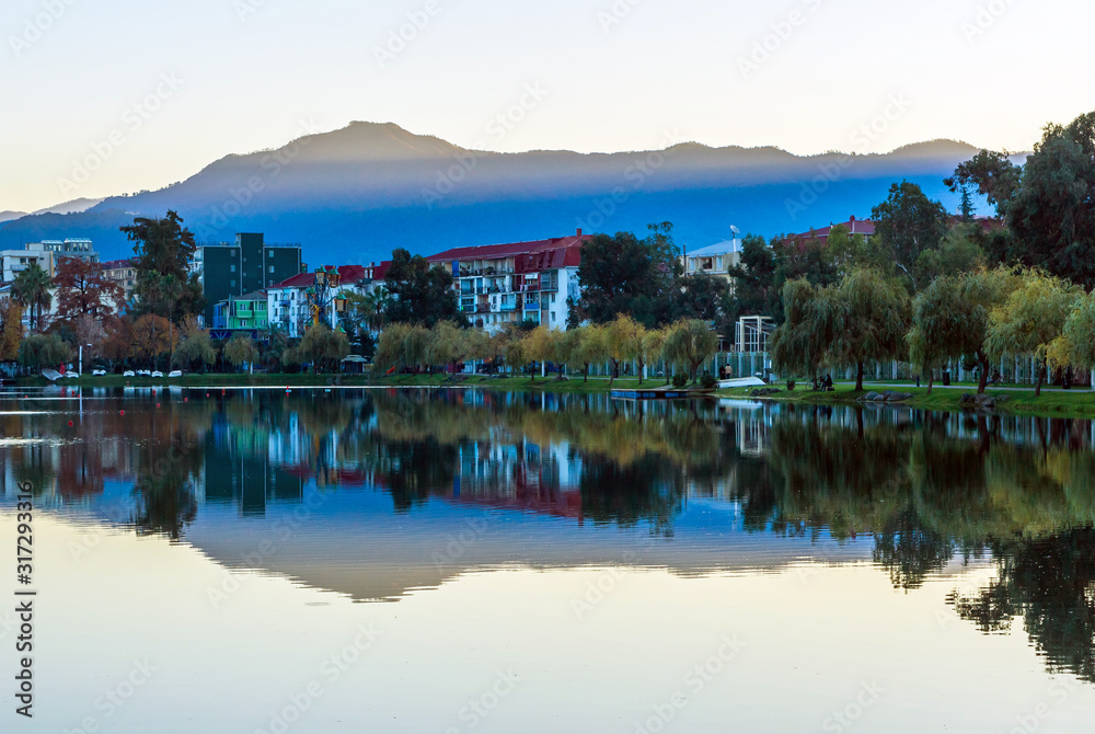 Lake in Batumi, Georgia. Early morning, the city and trees are reflected in the water.