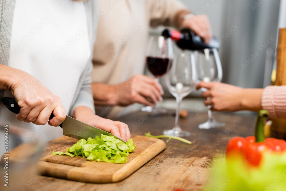 cropped view of woman cutting green lettuce on cutting board