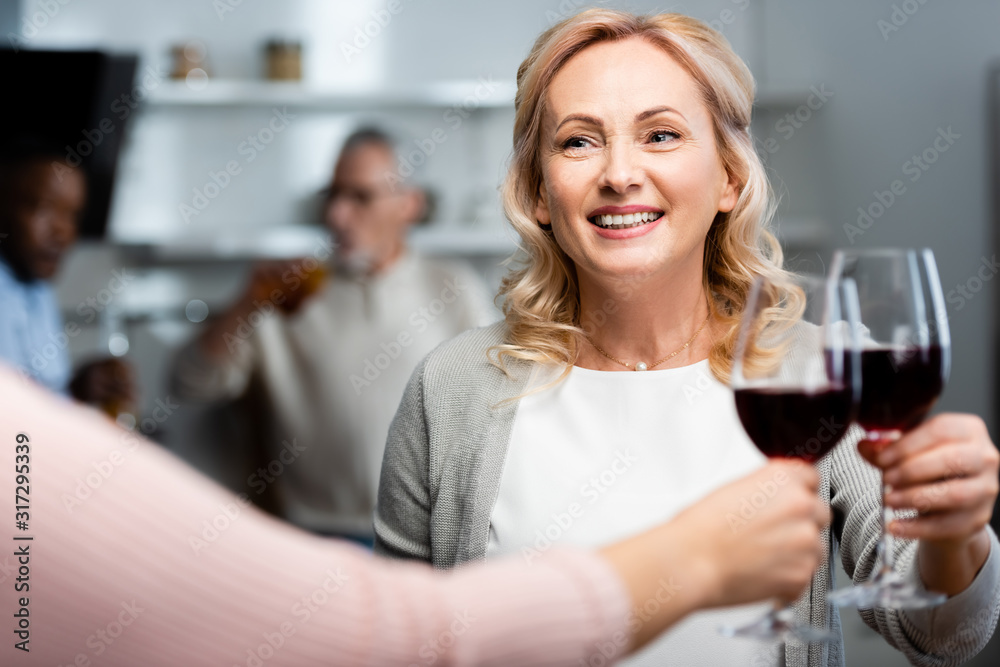 cropped view of woman clinking with smiling and attractive friend cropped view of woman clinking with smiling and attractive friend