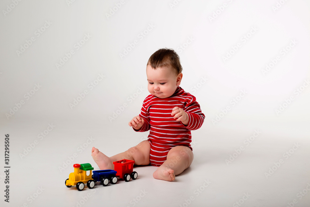 baby boy in red bodysuit sitting playing with a toy on a white background baby boy in red bodysuit sitting playing with a toy on a white background