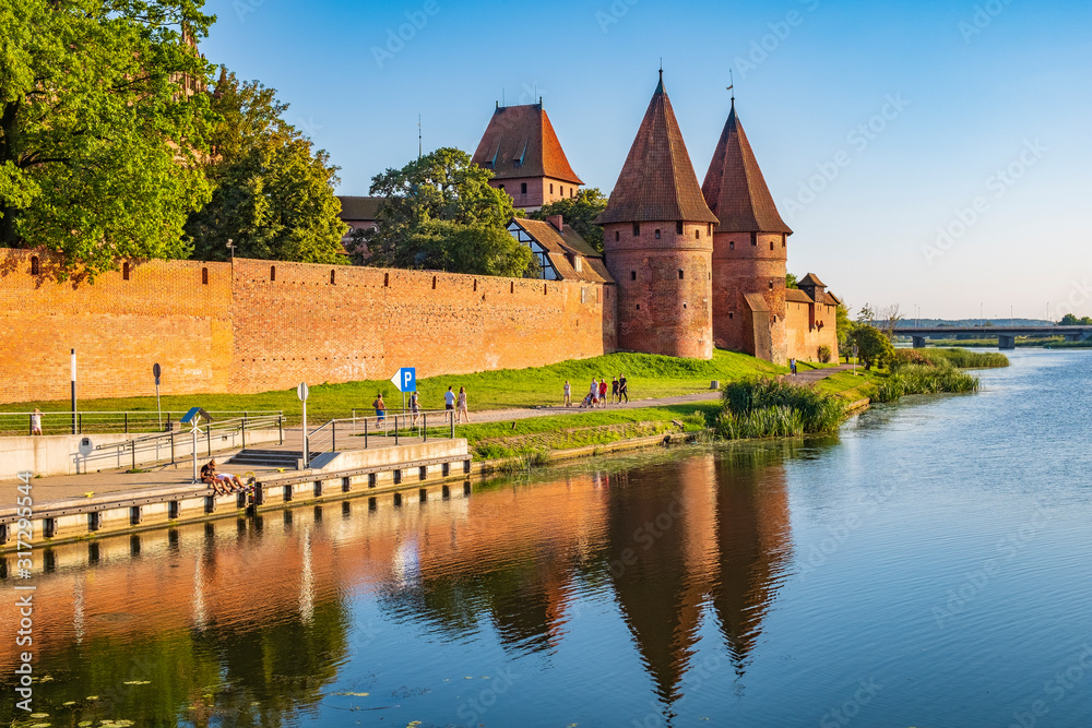 Naklejka premium Panoramic view of the western gate with defense towers of the Medieval Teutonic Order Castle in Malbork, Poland at the Nogat river bank