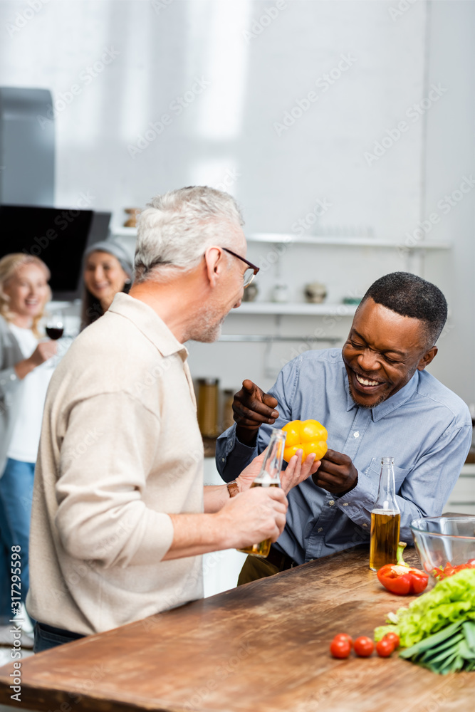 smiling african american man pointing with at his friend with bell pepper smiling african american man pointing with at his friend with bell pepper