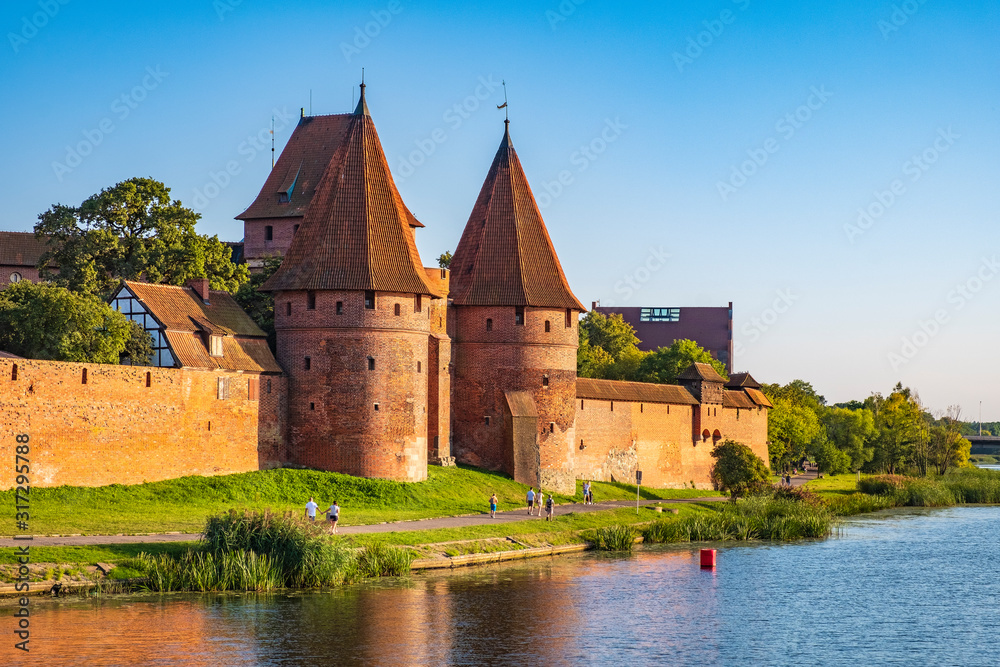 Panoramic view of the western gate with defense towers of the Medieval Teutonic Order Castle in Malbork, Poland at the Nogat river bank