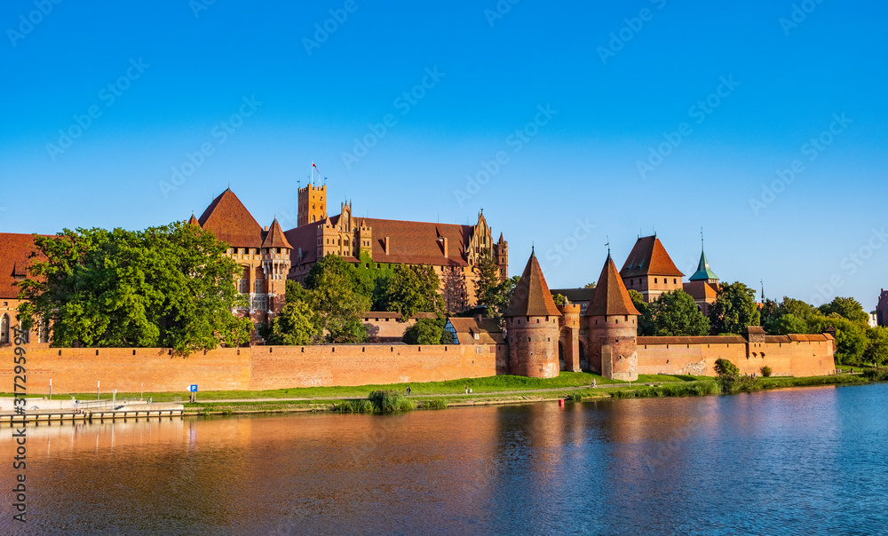Naklejka premium Panoramic view of the defense walls and towers of the Medieval Teutonic Order Castle in Malbork, Poland from across the Nogat river