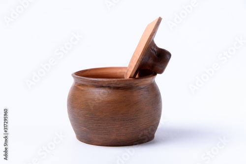 Clay pot with a spoon on a white background. The concept of making tasty and healthy food.