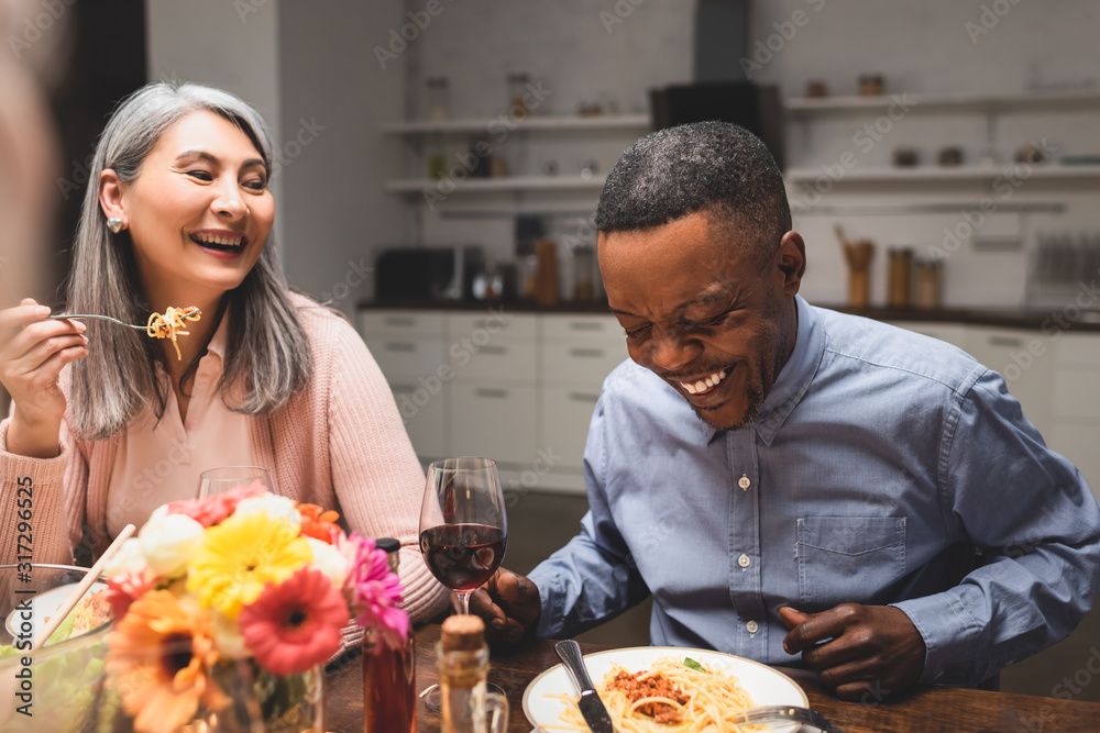 african american man and asain woman smiling during dinner