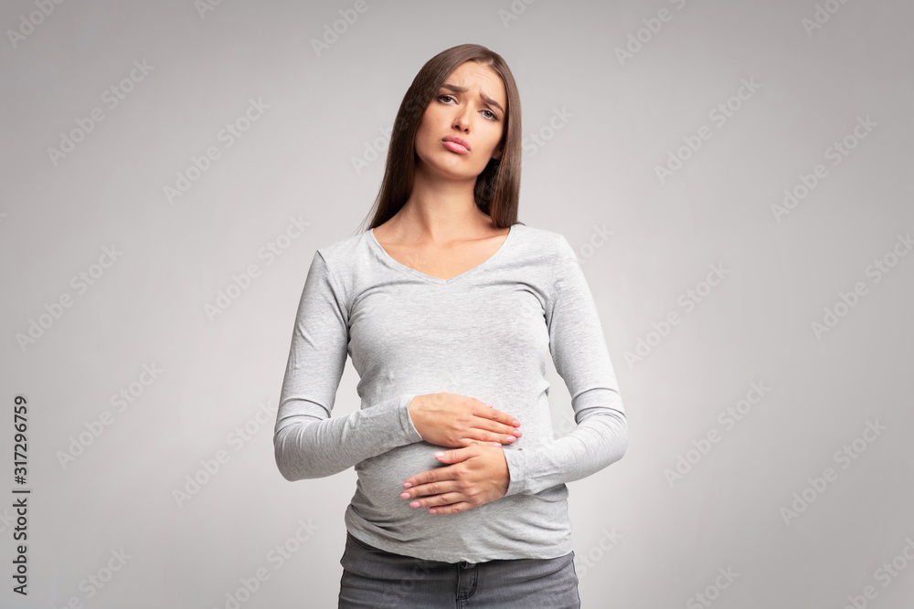 Unhappy Pregnant Lady Touching Aching Belly Standing Over Gray Background Unhappy Pregnant Lady Touching Aching Belly Standing Over Gray Background