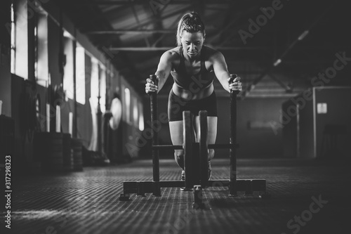 Female fitness model pushing a sled in a cross fit gym.