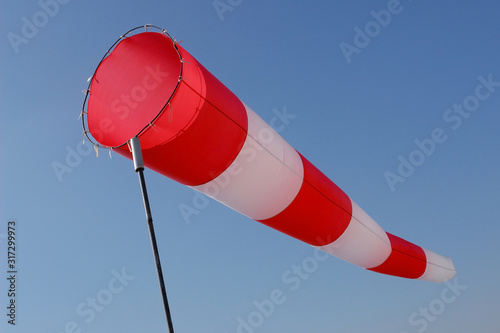 Red and white windsock on sky background