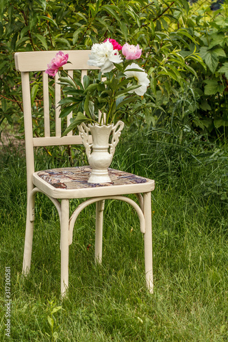 Vase of flowers on a white chair in the garden.