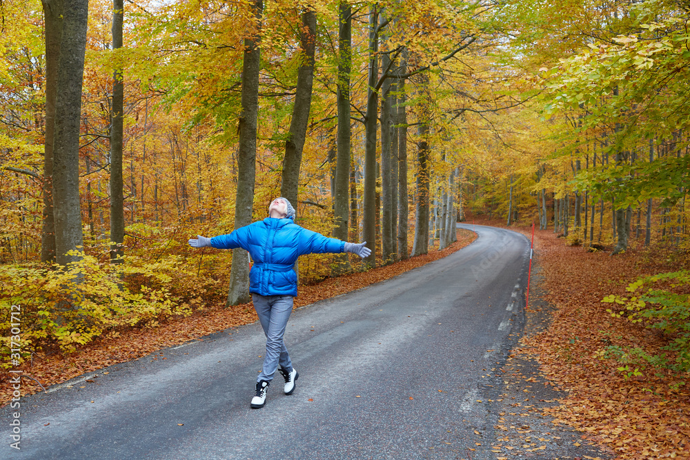 Fototapeta premium Young woman posing in the autumn forest on the road.