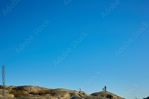 Silhouette of young active man with bicycle standing and looking forward at mountains panoramic background