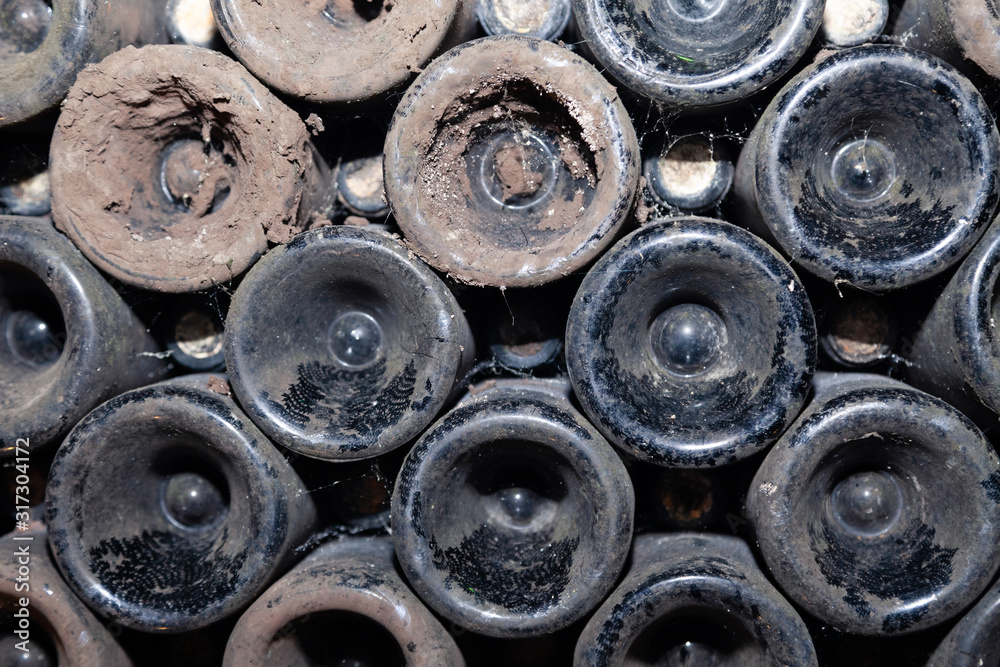Closeup pattern from bottom of old dark dusty wine bottles in rows in cellar, basement, wine warehouse, winery. Concept vault with old rare wines, exclusive collection rare bottle. Mosaic background Closeup pattern from bottom of old dark dusty wine bottles in rows in cellar, basement, wine warehouse, winery. Concept vault with old rare wines, exclusive collection rare bottle. Mosaic background