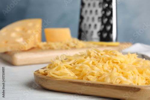 Delicious grated cheese on white wooden table, closeup