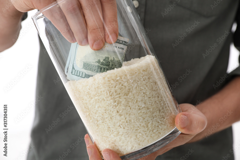Man hiding money in jar of rice indoors, closeup. Financial savings Stock  Photo