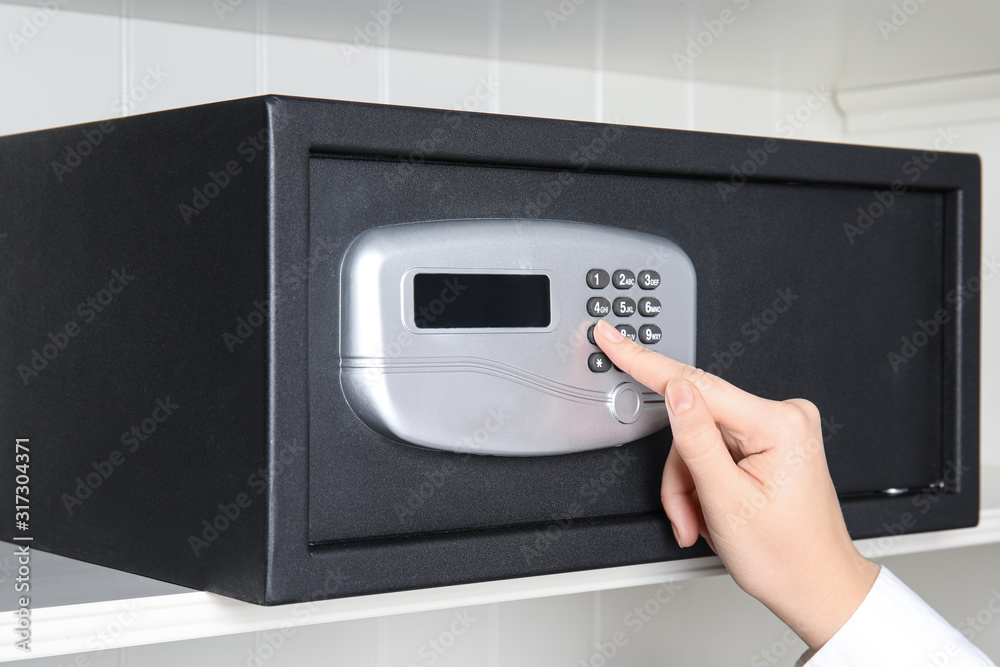 Woman opening steel safe with electronic lock, closeup Woman opening steel safe with electronic lock, closeup