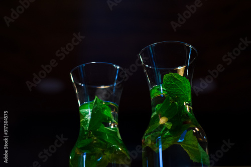 Decanters with useful water with grenade and fresh mint in dark. Vitamins. Detox.