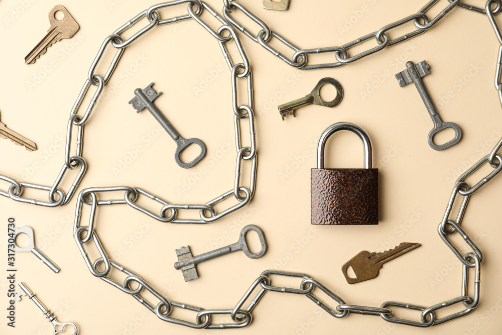 Steel padlock, keys and chain on beige background, flat lay. Safety concept