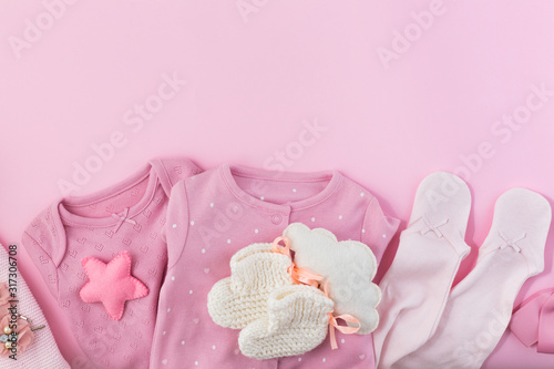 Pink background with clothes, socks and toys for a newborn girl. 