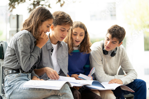 Teenage friends studying while sitting outdoors