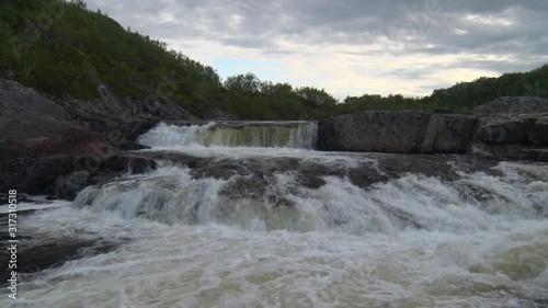 Stormy River Among Rocks.	The flow of water with noise falls with stones on river. Picturesque waterfall on a mountain river