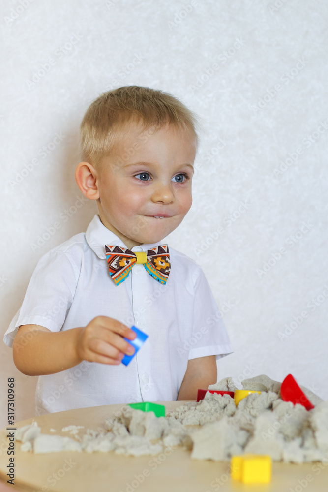A 2 year old Toddler Boy Is Playing With Kinetic Sand And Colorful