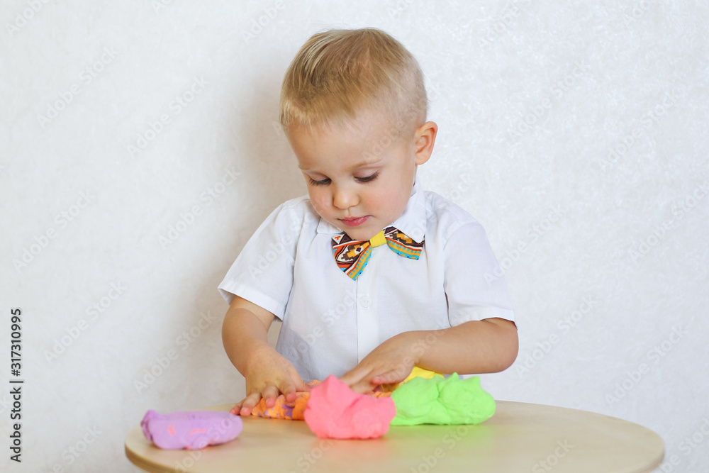 Toddler boy eagerly playing with kinetic plasticine, a great sensory activity to develop fine motor skills in young children Toddler boy eagerly playing with kinetic plasticine, a great sensory activity to develop fine motor skills in young children