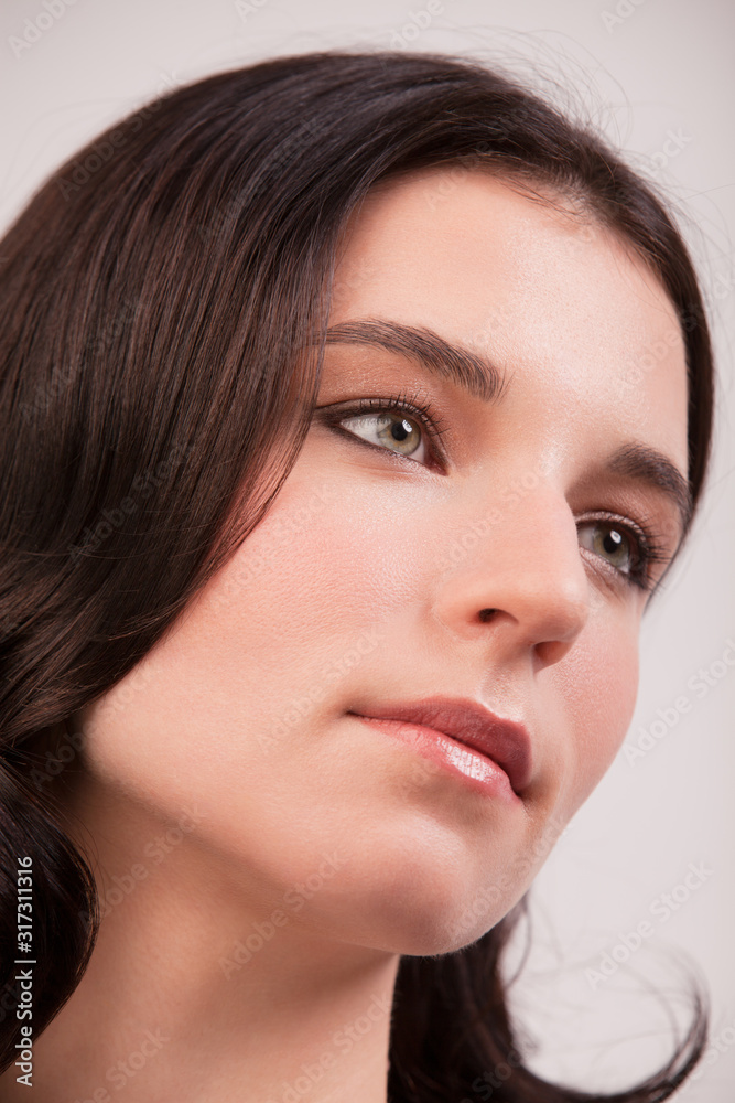Close up face of a young woman with clean fresh skin and dark hair. Young woman looks away from the camera Close up face of a young woman with clean fresh skin and dark hair. Young woman looks away from the camera
