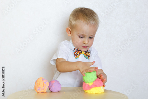 Toddler boy eagerly playing with kinetic plasticine, a great sensory activity to develop fine motor skills in young children