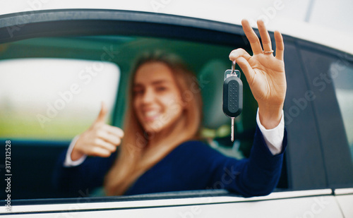 Young blonde woman in her new car smiling.
