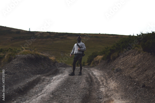 A hiker with a backpack walking on the road in the mountains.It's a dark time before the thunderstorm