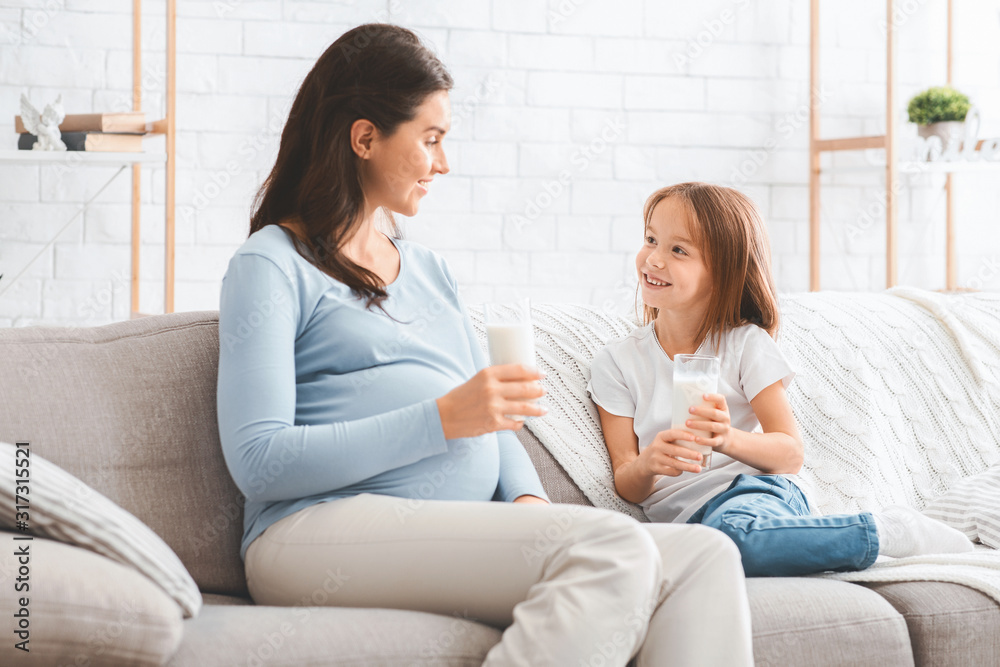 Pregnant loving mom drinking milk with her sweet daughter Pregnant loving mom drinking milk with her sweet daughter